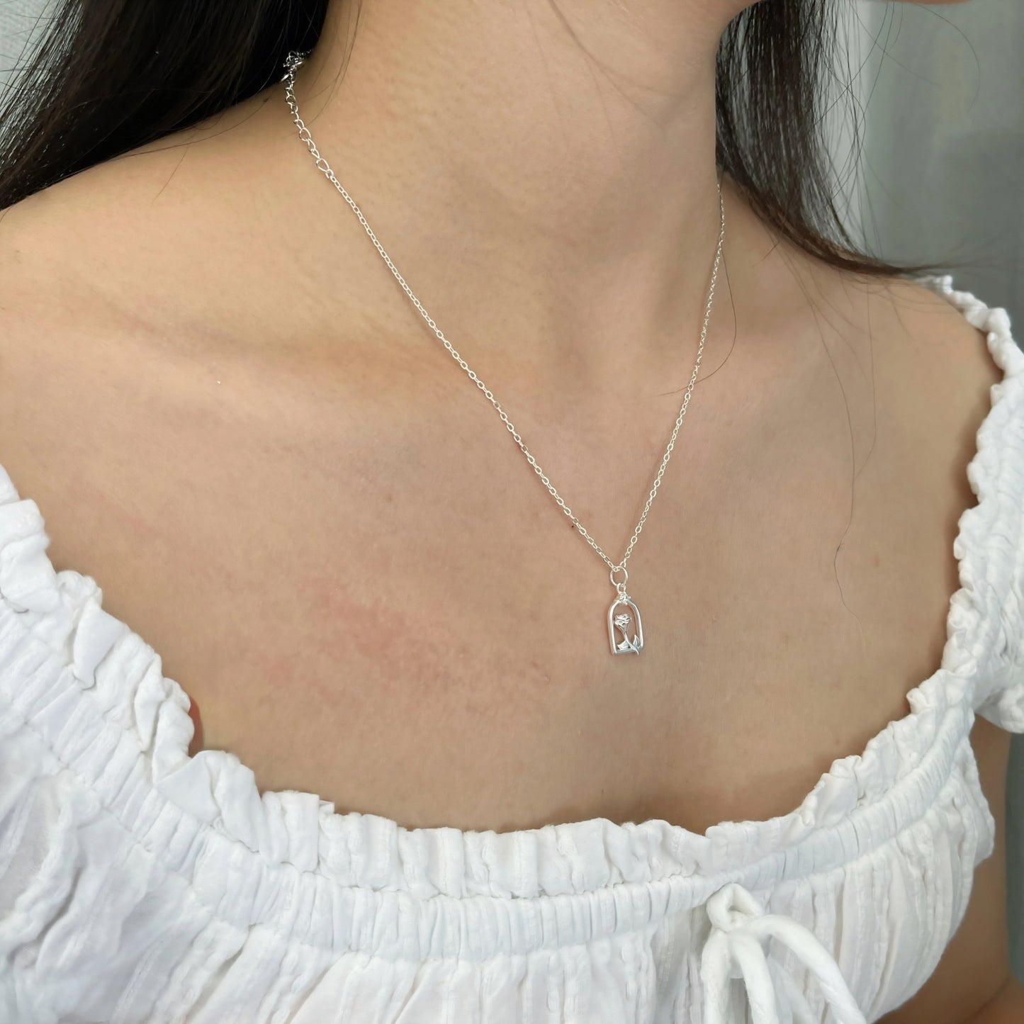 Close-up of a woman wearing a silver flower necklace.