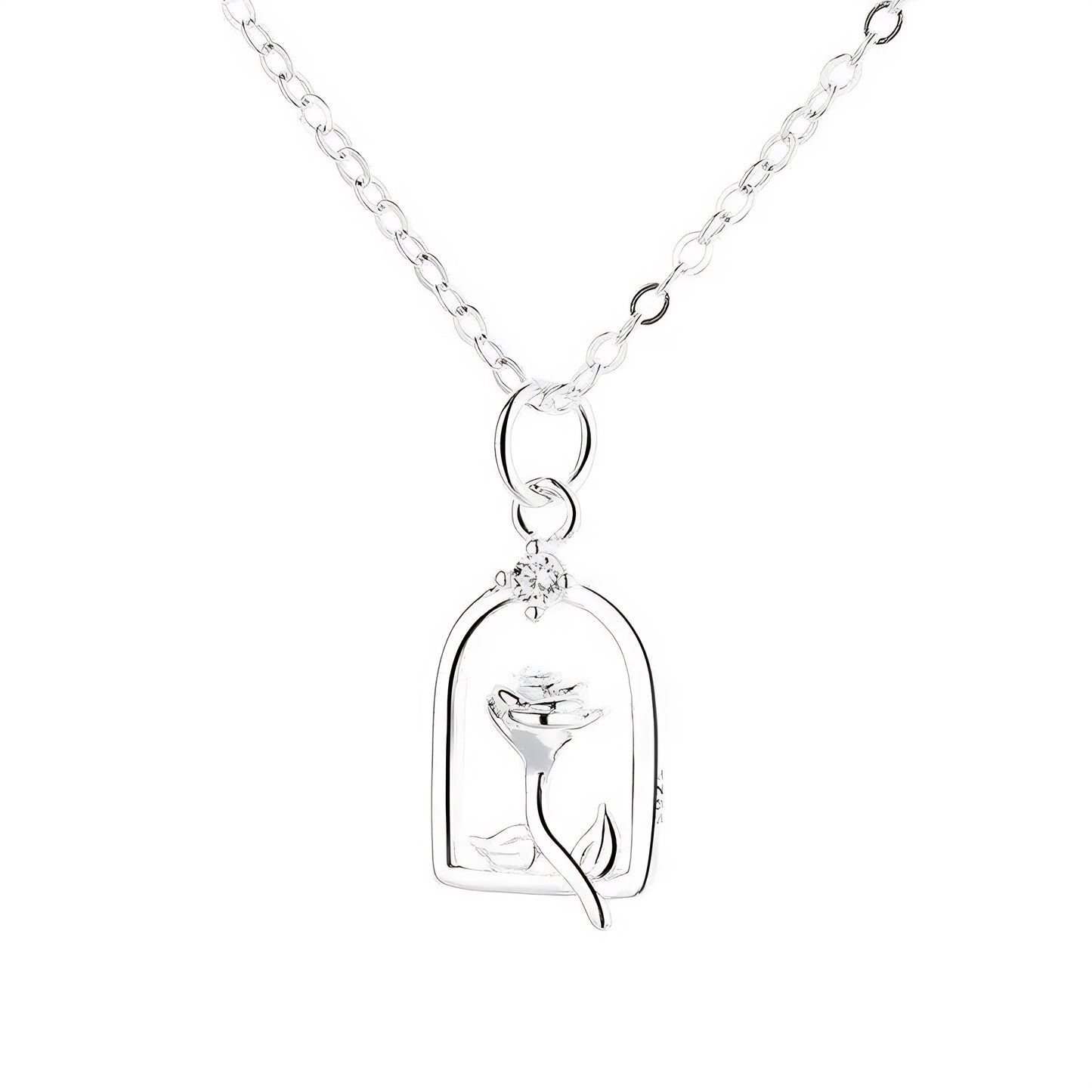 Gold necklace with a rose-shaped pendant, outlined in a archway and featuring small white stones.