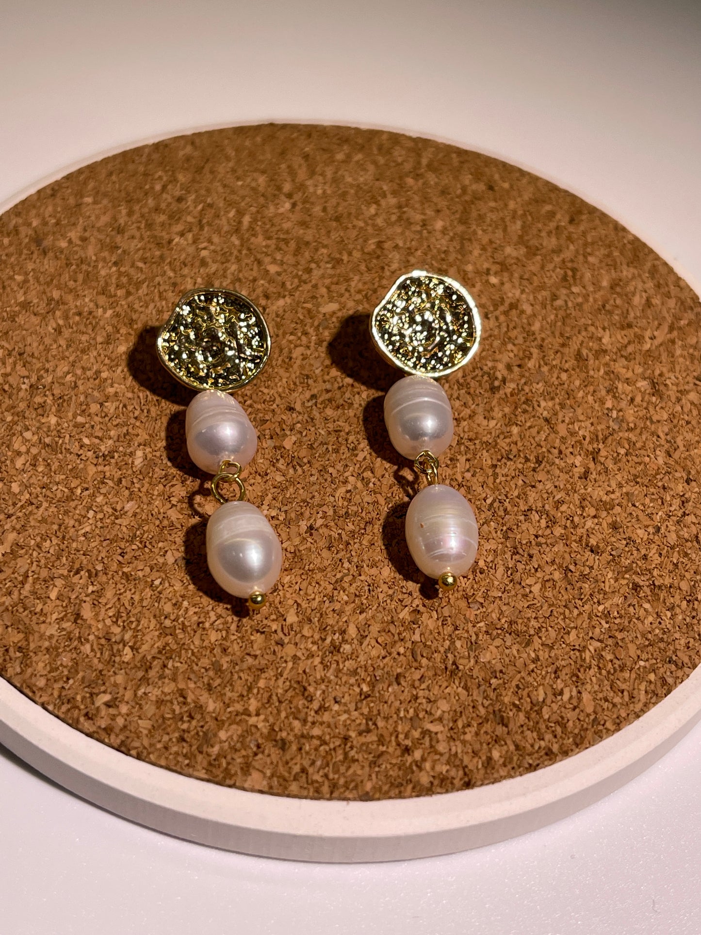Pair of gold-toned earrings with textured discs and pearl drops.