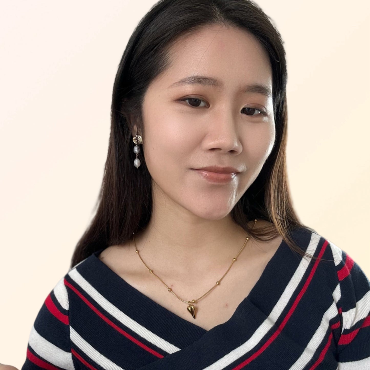 Close-up of a woman wearing Pair of gold-toned earrings with textured discs and pearl drops.