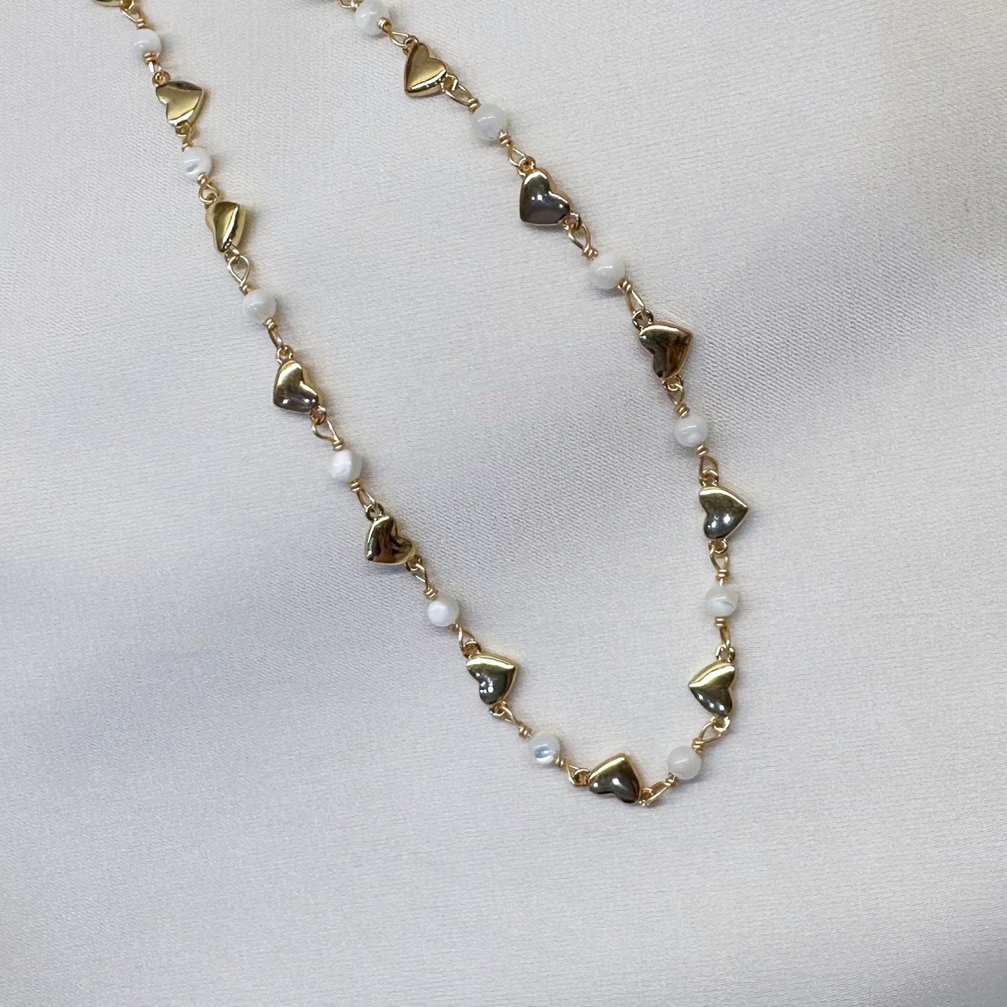 Gold chain adorned with small heart-shaped charms, elegantly showcasing a delicate and romantic design.