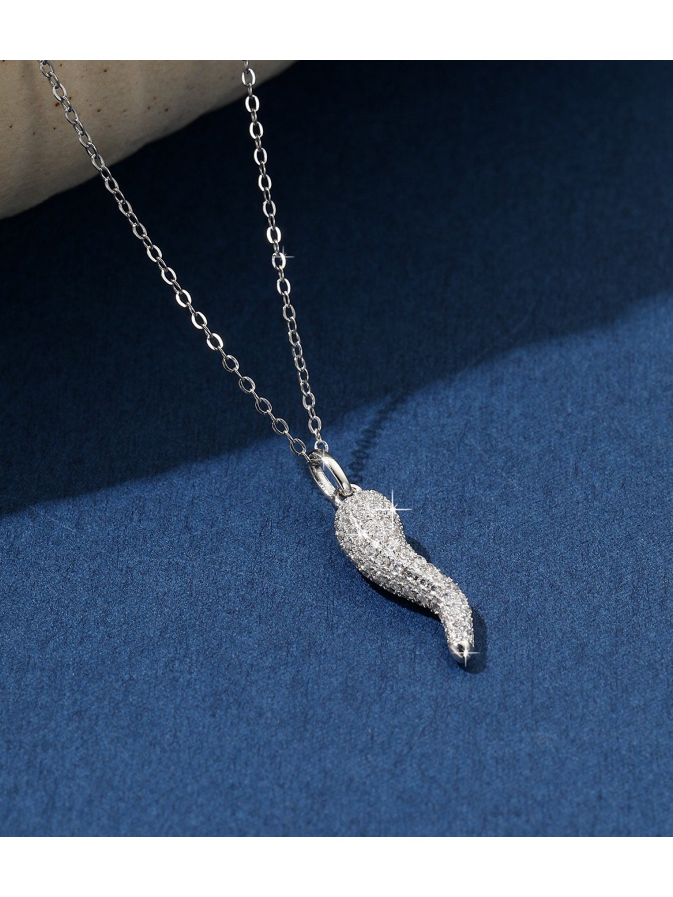 Delicate silver necklace with a small, horn-shaped pendant adorned with tiny crystals.