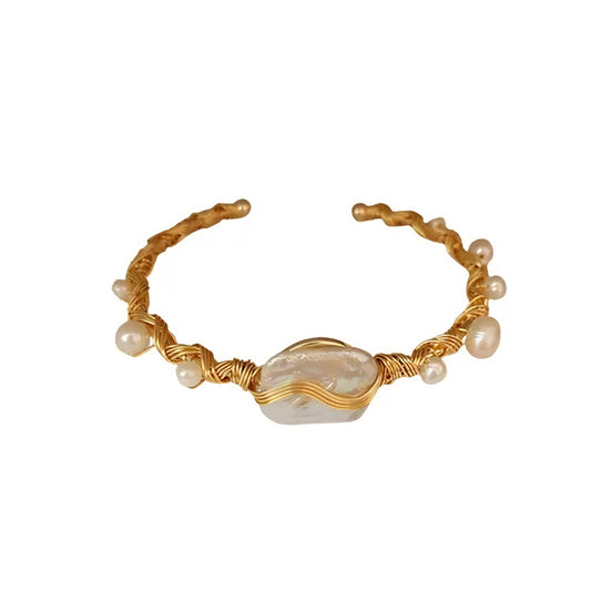 Gold wire-wrapped bracelet with a large, iridescent baroque pearl and smaller pearls.