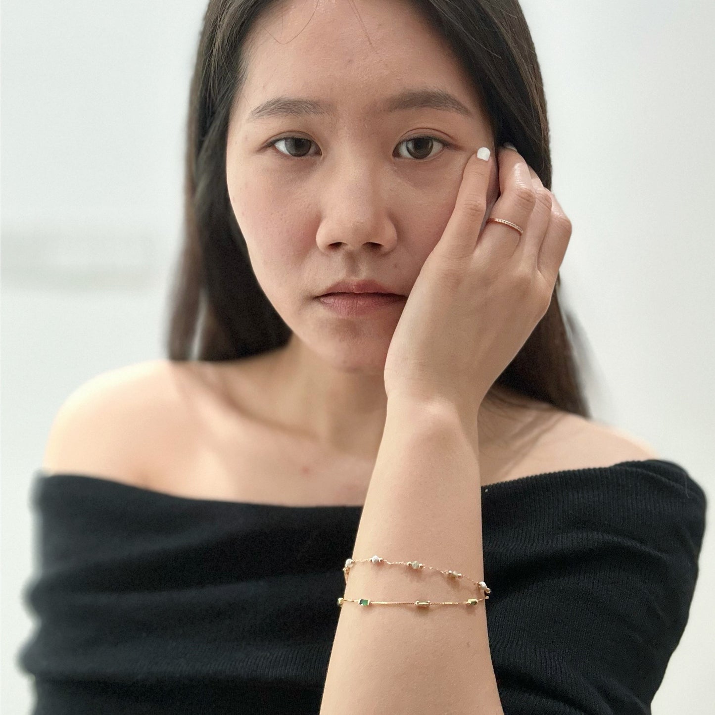 Close up a woman wearing gold-toned beaded bracelet with various colored and patterned beads.