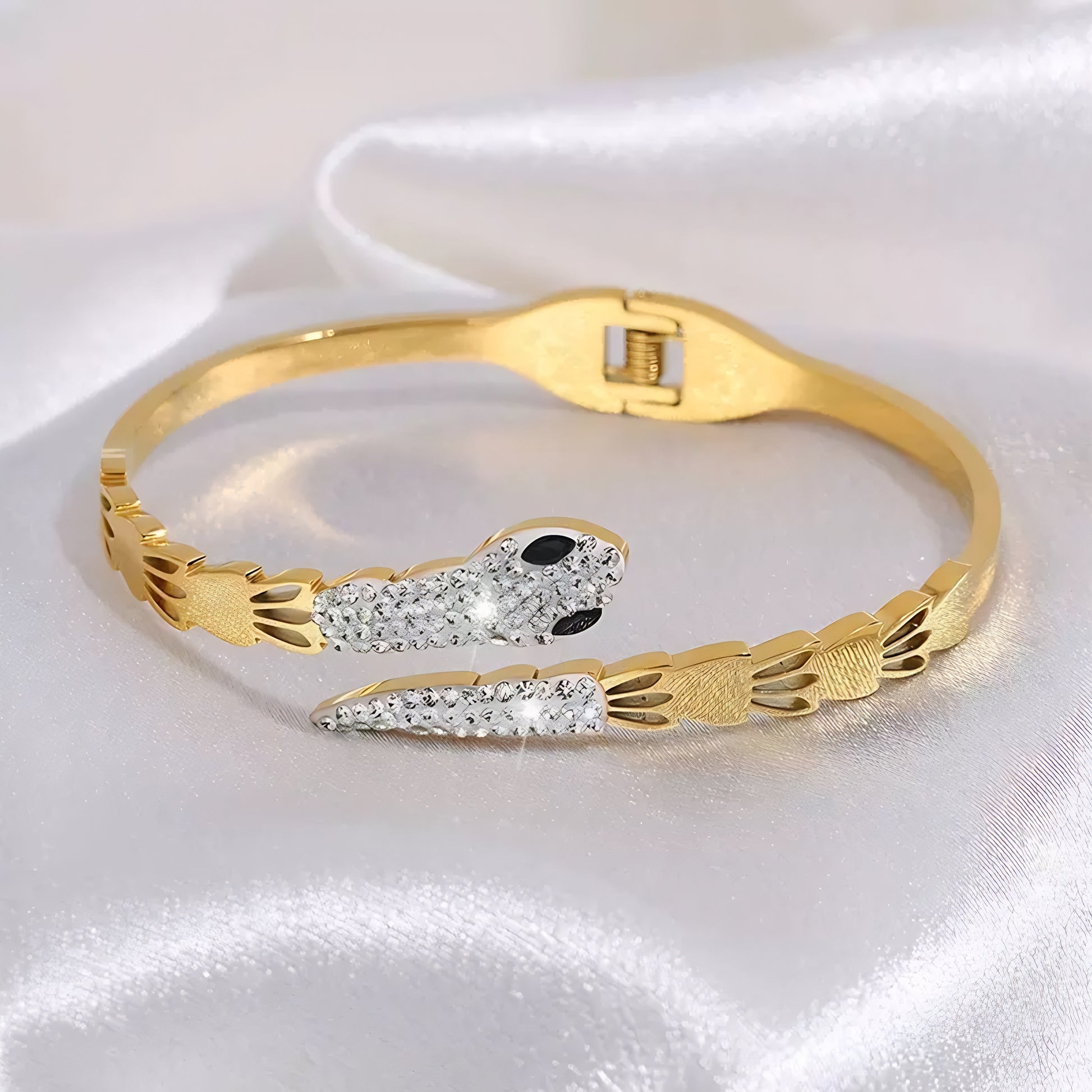 Gold bangle bracelet with a snake design, featuring clear and black crystals.