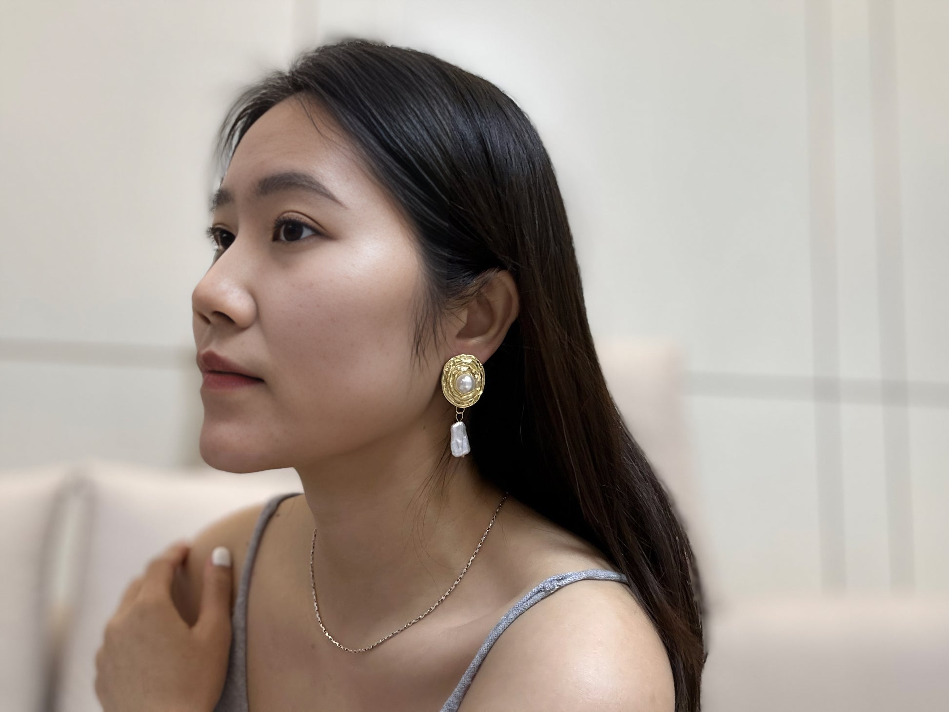 Close-up of a woman wearing a delicate dangle classic earrings.