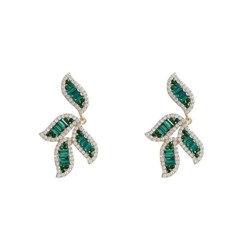 Gold-toned earrings featuring leaf-shaped designs adorned with baguette-cut green crystals and white cubic zirconia.