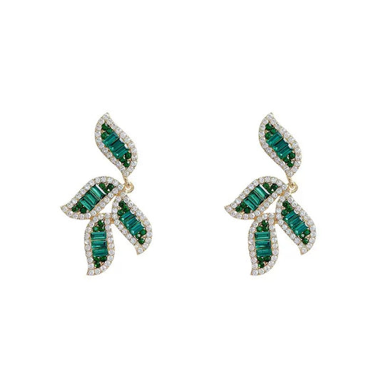 Gold-toned earrings featuring leaf-shaped designs adorned with baguette-cut green crystals and white cubic zirconia.