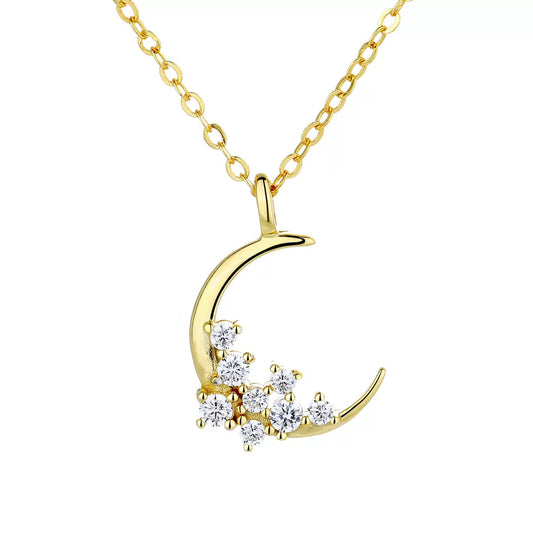 A luxurious gold crescent necklace embellished with diamonds, presented on a simple, light-colored surface.