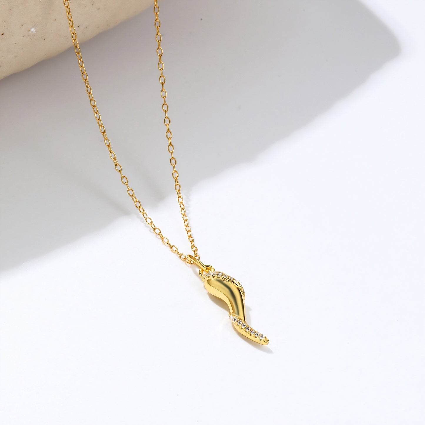 Delicate gold plated necklace with a small, horn-shaped pendant adorned with tiny crystals.