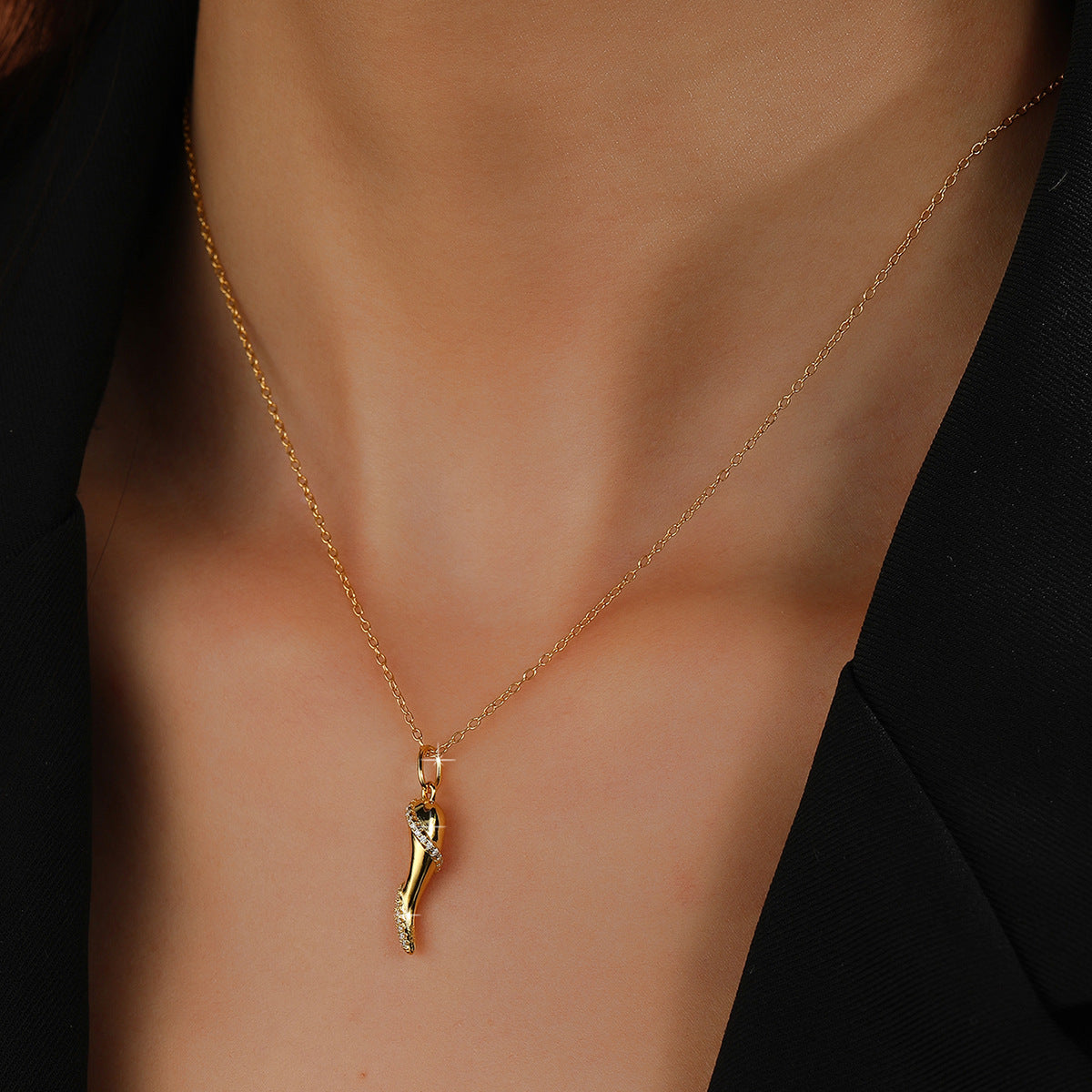 Delicate gold plated necklace with a small, horn-shaped pendant adorned with tiny crystals.