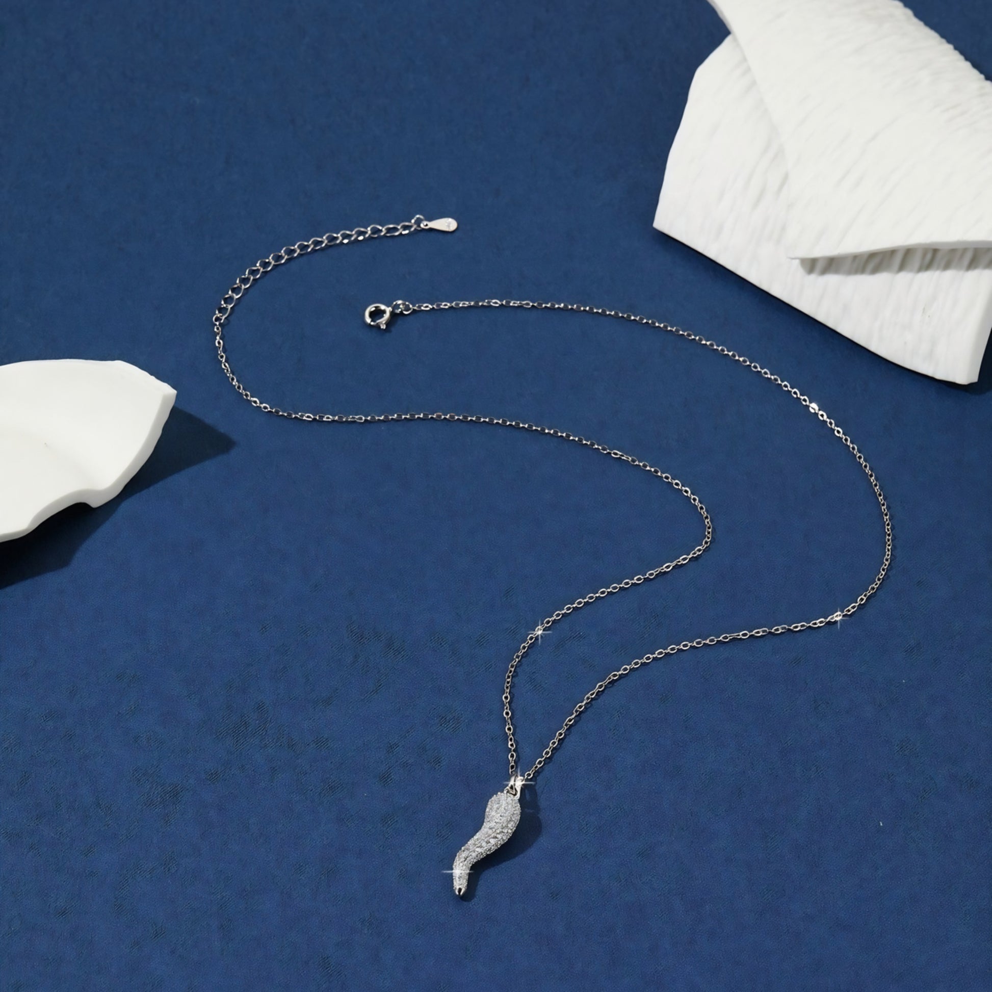 Silver necklace with a horn-shaped pendant, studded with small white stones.