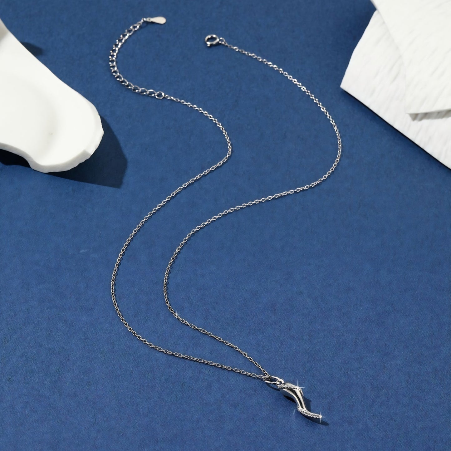 Silver necklace with a stylized horn-shaped pendant, detailed with small diamonds.