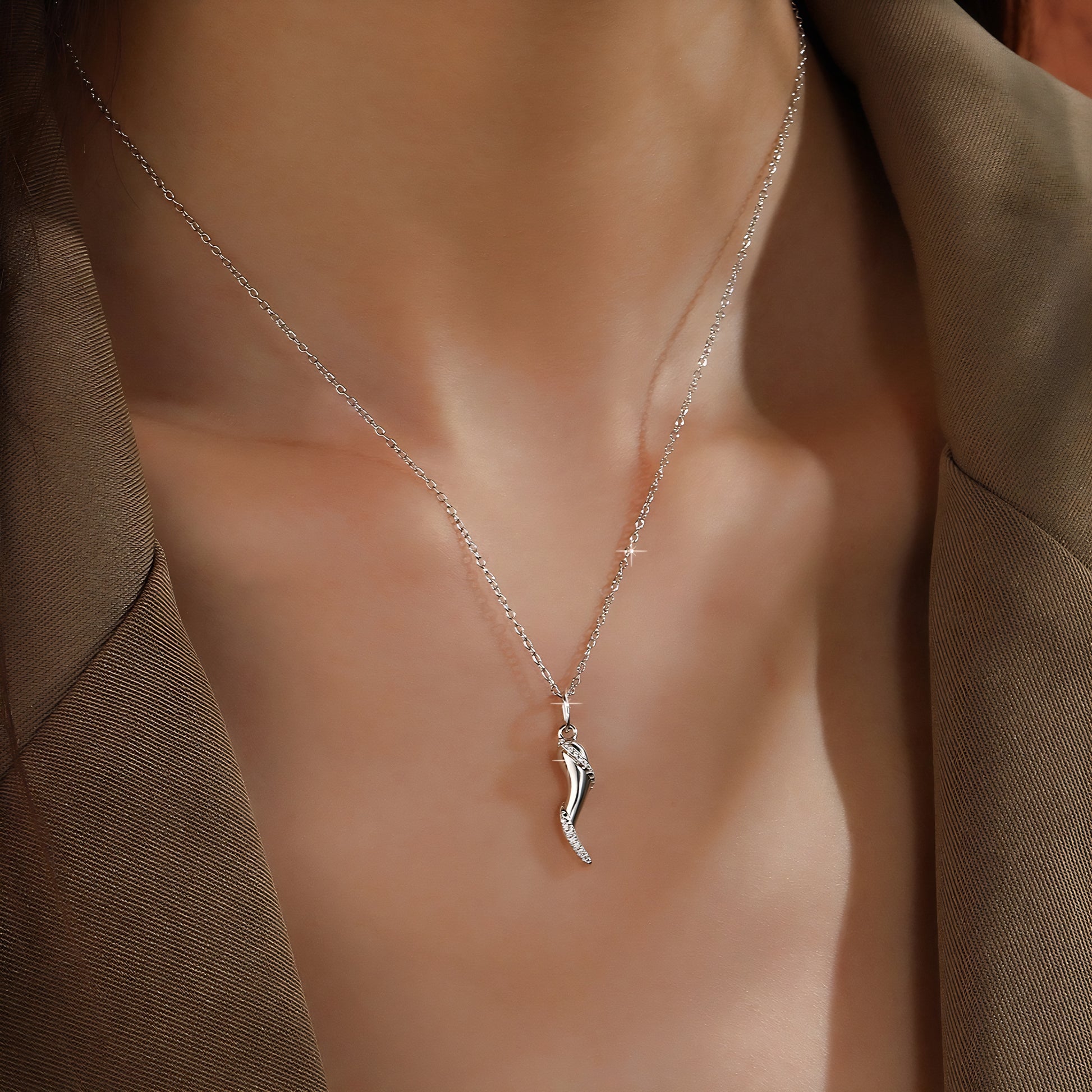 Delicate silver necklace with a small, horn-shaped pendant adorned with tiny crystals.