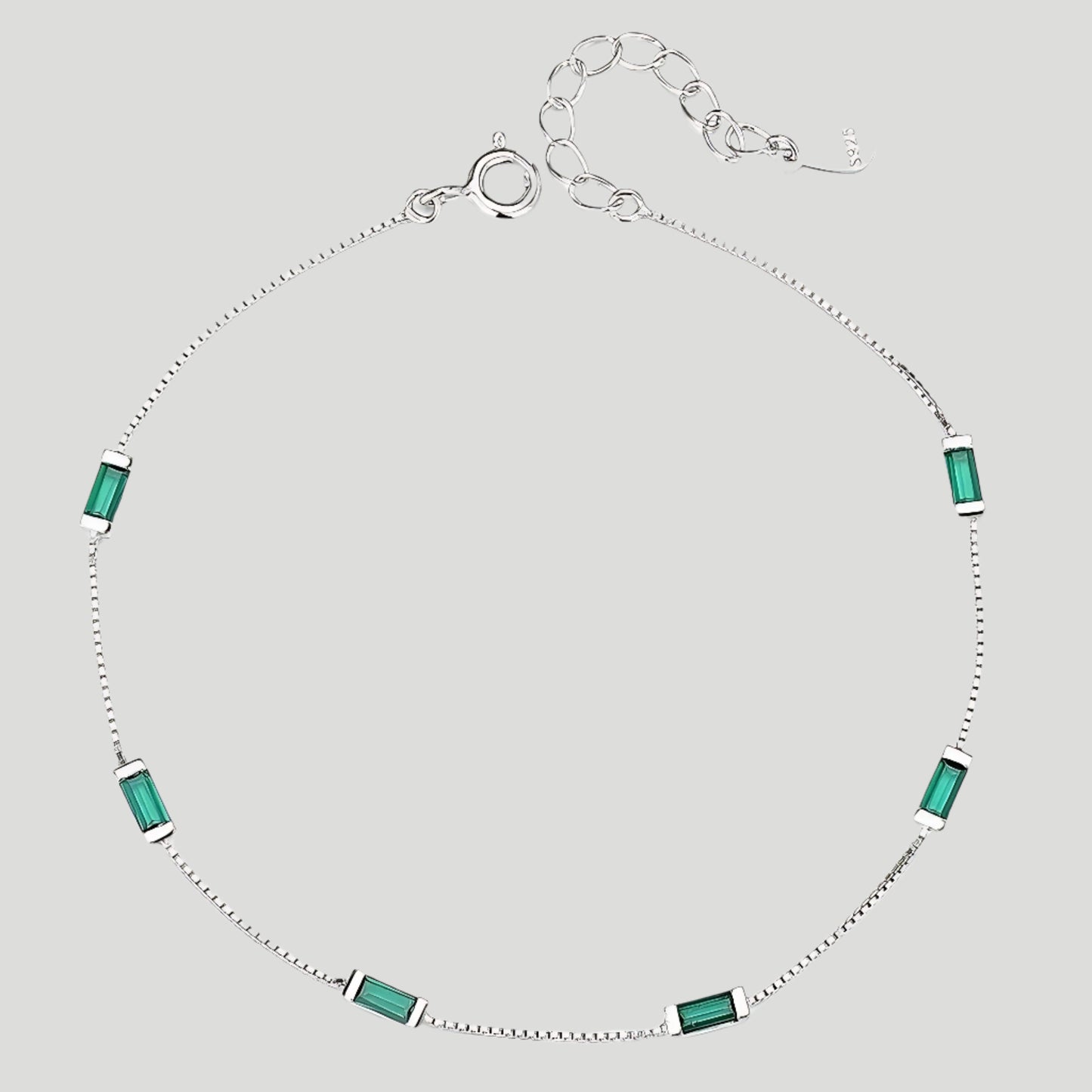Delicate silver bracelet with six emerald-cut green stones.