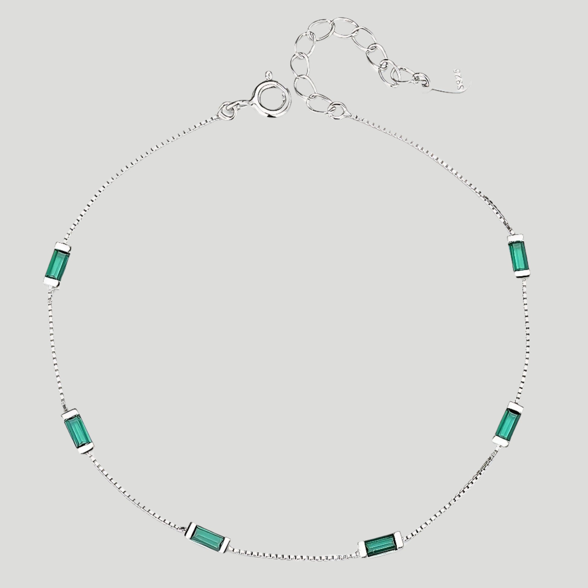 Delicate silver bracelet with six emerald-cut green stones.