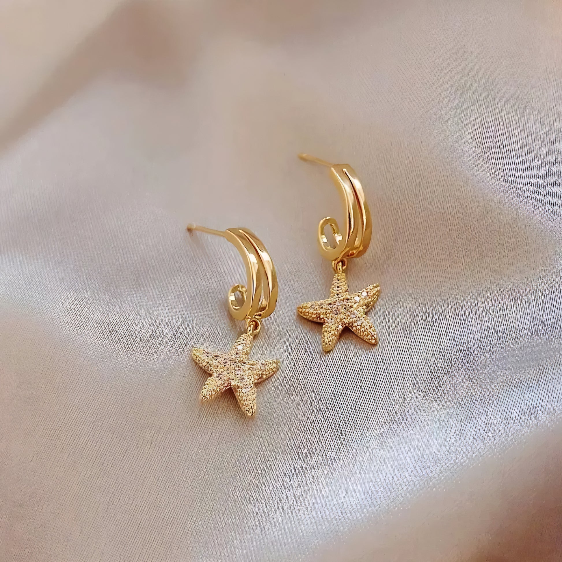 Pair of gold-tone, starfish-shaped earrings with small white crystals.