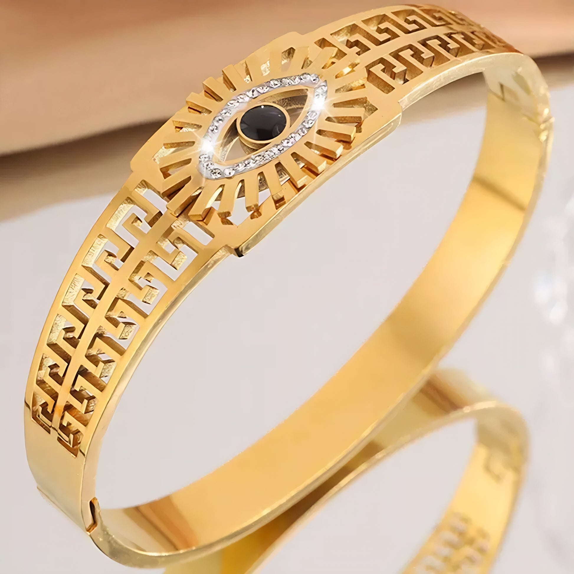 Gold bracelet with intricate Greek key details and a beautiful eye.