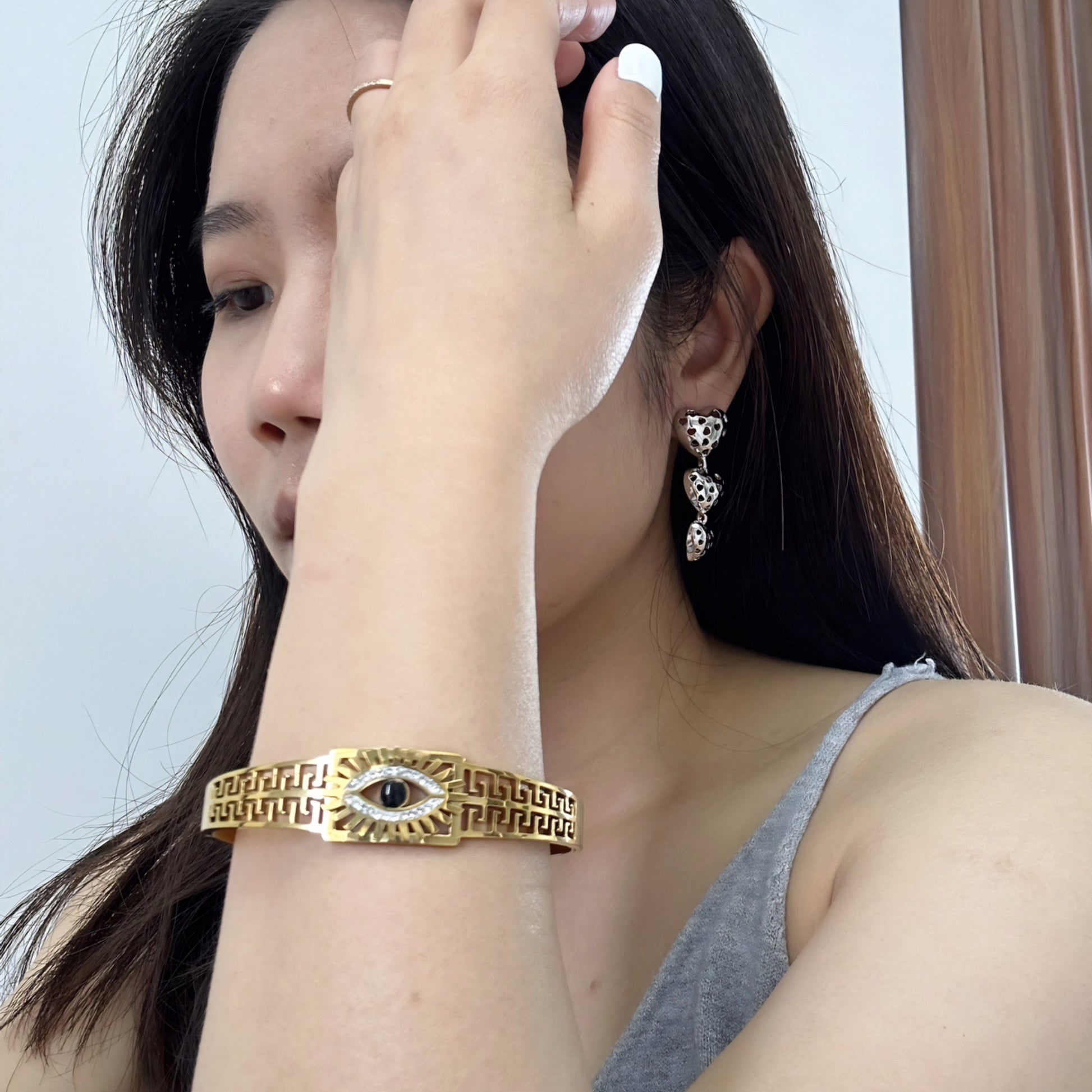 Close-up of a woman wearing gold bangle bracelet with a snake design, featuring clear and black crystals.